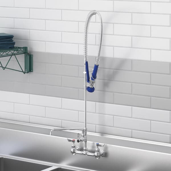 A Waterloo wall-mounted pre-rinse faucet with an add-on faucet above a sink in a school kitchen.