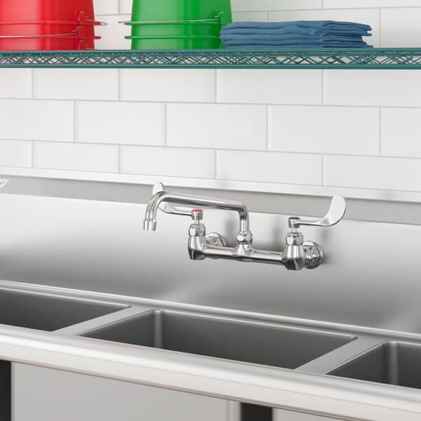 A stainless steel sink with Waterloo wall-mounted faucet and three bins.