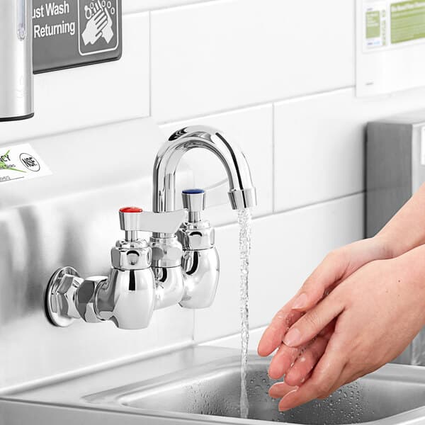 A person washing their hands under a Waterloo wall mount faucet.