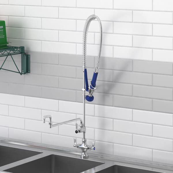 A Waterloo deck-mounted pre-rinse faucet with a double-jointed add-on faucet over a kitchen sink.