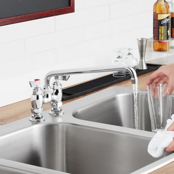 A hand washing a glass in a sink with a Waterloo swing spout.