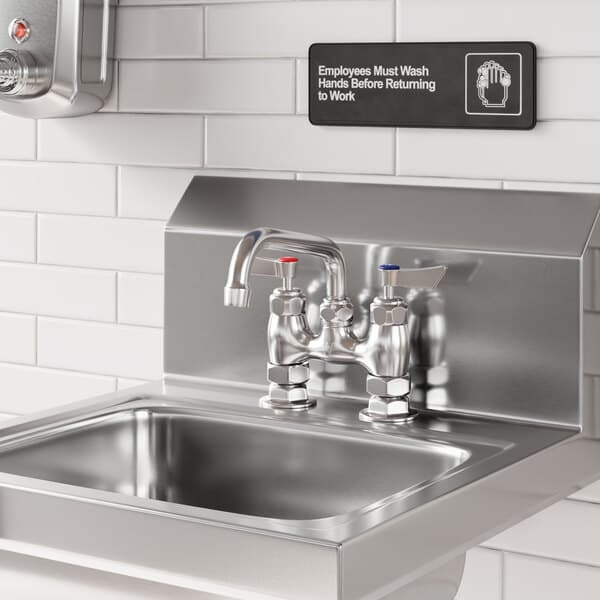 A stainless steel deck-mounted faucet with 4-inch centers and a 6-inch swing spout installed on a commercial sink.