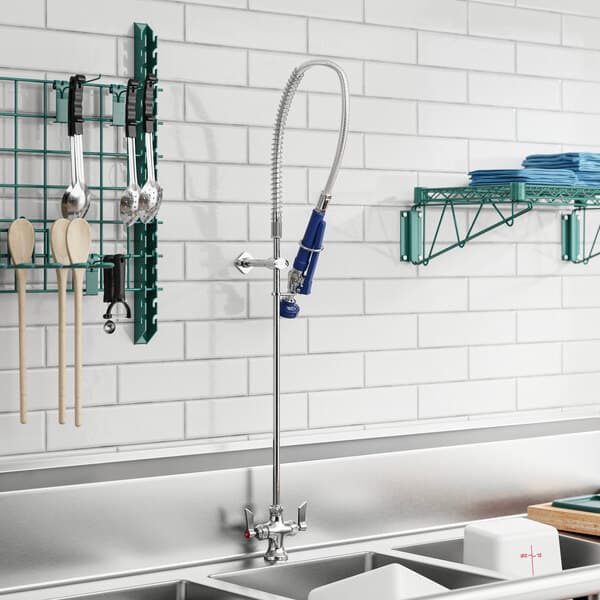 A kitchen sink with a Waterloo pre-rinse faucet over a rack of dishes.
