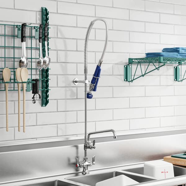 A white kitchen sink with a Waterloo pre-rinse faucet and a rack of dishes above it.