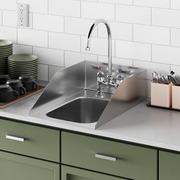 A Waterloo stainless steel drop-in sink with side splashes in a green kitchen with white tile.