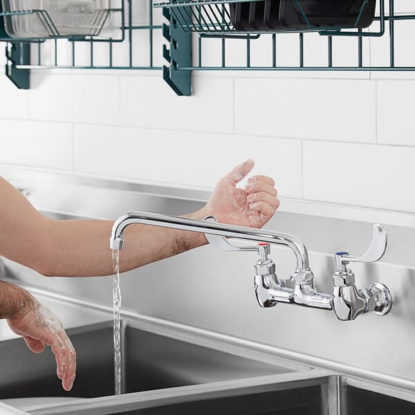 A person using a Waterloo Wrist Blade faucet handle to wash their hands under a faucet.