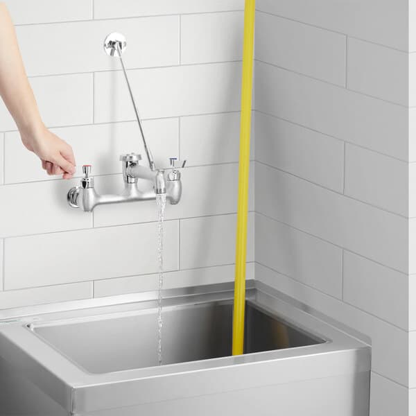 A person using a Waterloo wall-mounted mop sink faucet to wash their hands over a sink.