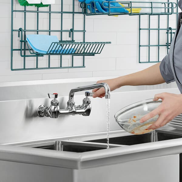A woman using a Waterloo hot/cold faucet handle to wash dishes in a sink.