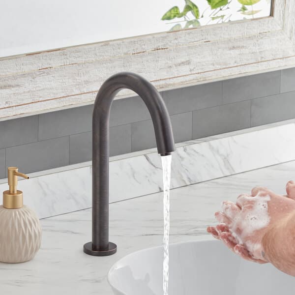 A person washing their hands under a Waterloo deck-mount hands-free faucet.